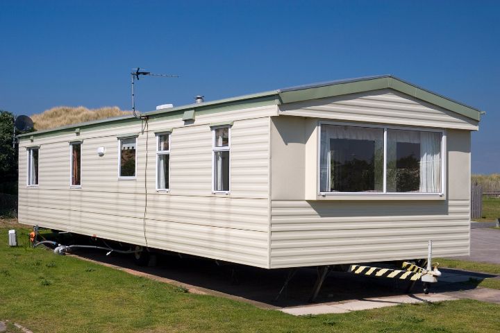 white static caravan in a field on a sunny day