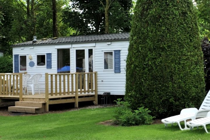 Static caravan with decking and surrounded by grass and bushes