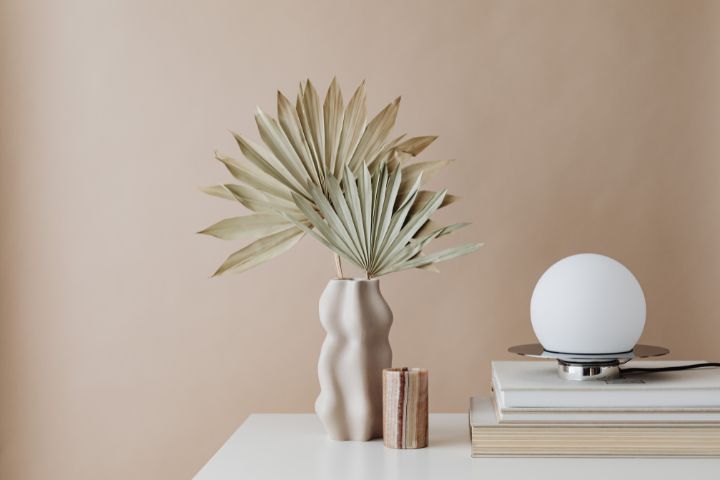 A vase with plants and a round light next to it
