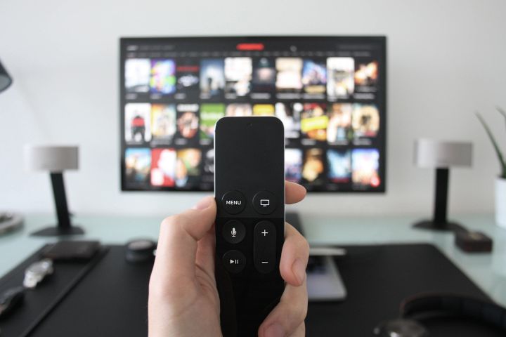 TV with streaming services on it and person holding a remote