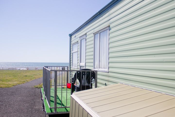 Outside of a static caravan with a balcony area looking over the beach