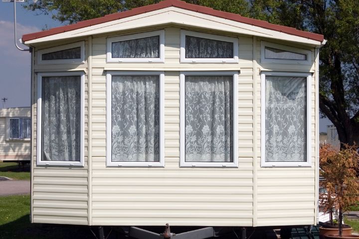 Front view of a static caravan. Shows windows with net curtains