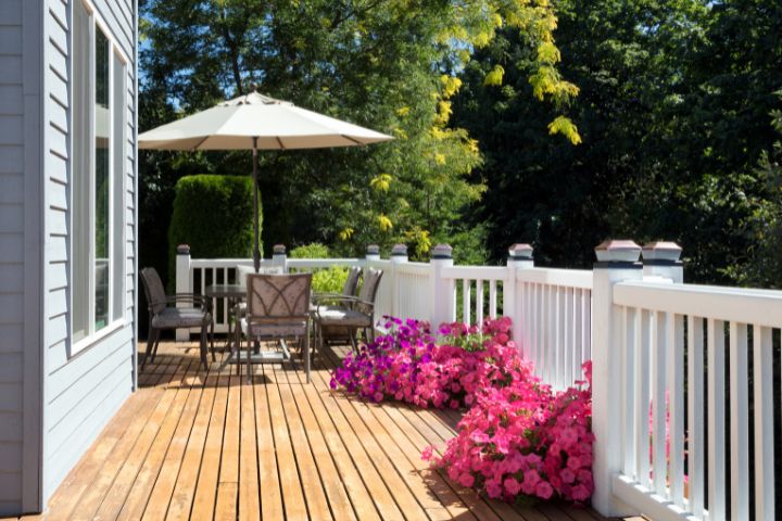 Decking with wooden fencing, plants and a seating area with an umbrella