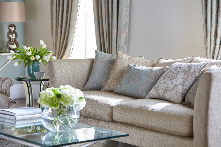 modern beige sofa with patterned cushions with a glass coffee table